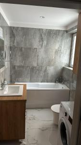 uma casa de banho com uma banheira, um lavatório e um WC. em Apartament 33 Park City em Ostrów Wielkopolski