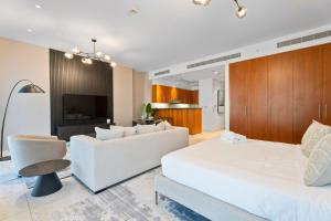 Nasma Luxury Stays - Modern Studio Apartment with City View In DIFC في دبي: غرفة معيشة مع أريكة بيضاء وتلفزيون