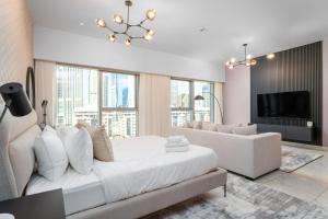 a white bedroom with a large bed and a couch at Nasma Luxury Stays - Modern Studio Apartment with City View In DIFC in Dubai