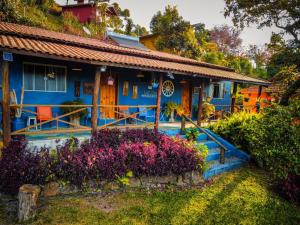 ein blaues Haus mit Blumen davor in der Unterkunft Chalés lá na roça in Costas