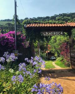 a gate to a garden with purple flowers at Chalés lá na roça in Costas