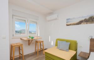 een kamer met een groene stoel, een tafel en 2 ramen bij Nice Apartment In Rogotin With Kitchen in Rogotin