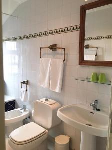 a white bathroom with a toilet and a sink at Casa de Castelo Novo in Castelo Novo