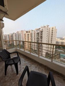 Un balcón con una silla y una mesa y algunos edificios en Aqua Inn - Studio Apartment, en Greater Noida