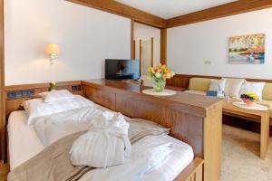 a bedroom with a bed and a desk with a television at Hotel Restaurant Falken in Baiersbronn