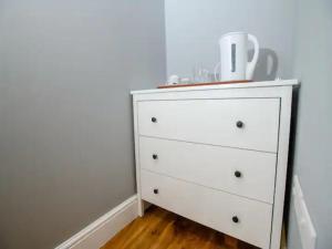 a white dresser in a corner of a room at Pass the Keys Garden Room in City Centre in Lincoln