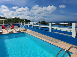 a swimming pool with chairs and a fence at Villa Oceane in Le Moule