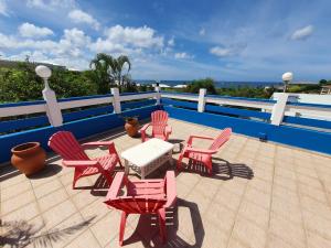 patio con sedie rosse e tavolo bianco di Villa Oceane a Le Moule