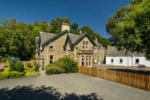 una gran casa de ladrillo con una valla de madera en Strathardle Lodge, en Kirkmichael