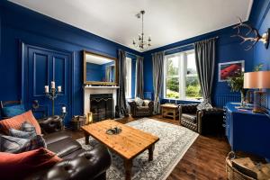 Sala de estar azul con sofá y mesa en Strathardle Lodge, en Kirkmichael