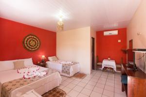 a bedroom with two beds and red walls at Pousada Boa Vista in Barreirinhas