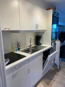 a kitchen with white cabinets and a sink at Genieten aan zee in De Haan in De Haan