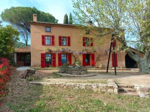 een groot huis met rode deuren en een boom bij Mas provençal dans un vignoble in La Motte