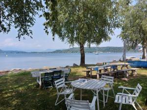 a group of tables and chairs next to a lake at Bnbook Lago Maggiore Studio 2 in Dormelletto