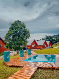 a swimming pool on a wooden deck with houses and a tree at Vale dos Imigrantes in Bento Gonçalves