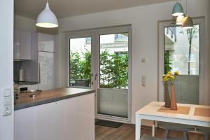 エッカーンフェルデにあるSTRANDMUSCHEL - 73512の白いキャビネットと花のテーブル付きのキッチンが備わります。
