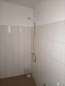 a white tiled bathroom with a shower in it at CAMPEMENT DIAMORAL DIAKENE OULOFF in Diakène Ouolof