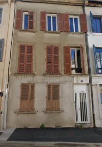 un vieux bâtiment avec des fenêtres à volets en bois et une rue dans l'établissement Le Majorelle-centre ville-accès 24h- parking free, à Montluçon