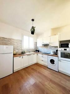 uma cozinha com armários brancos e um frigorífico branco em Merveilleux appartement style nature proche centre ville em Collioure