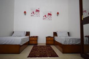 a room with two beds and a rug at Kony Nubian Guest House in Abu Simbel