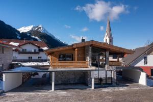 a wooden building with a church in the background at Alprocks Alvaresort in Bichlbach