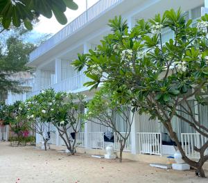 un edificio blanco con árboles delante de él en Seri Resort Gili Meno - Adults Only, en Gili Meno