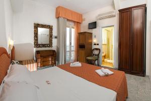 ミラノ・マリッティマにあるHotel Deaのベッドと鏡が備わるホテルルーム