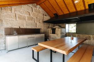 a kitchen with a wooden table and a stone wall at D'Autor Village in Valadares