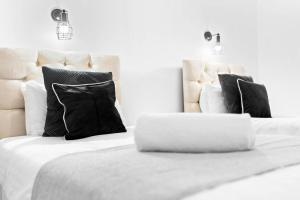 Una cama blanca con almohadas negras y un ordenador portátil. en Large Luxury 4 Bedroom House - Off-street Parking - Garden - Wifi - Netflix - 11M, en Northfield