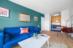 a living room with a blue couch and a table at Sunny Shoreditch Oasis Canal Views & Urban Charm in London