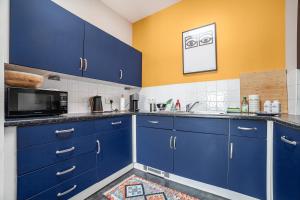 uma cozinha com armários azuis e um micro-ondas em Sunny Shoreditch Oasis Canal Views & Urban Charm em Londres