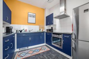 une cuisine avec des placards bleus et un mur jaune dans l'établissement Sunny Shoreditch Oasis Canal Views & Urban Charm, à Londres