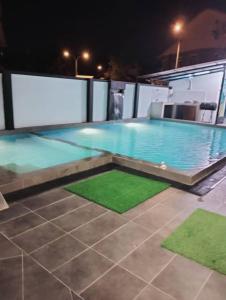- une piscine avec des tapis verts la nuit dans l'établissement Villa Nazrina Homestay, à Sungai Petani
