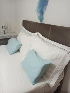 a bed with white pillows and blue pillows at Apartmani Mislav in Slatine