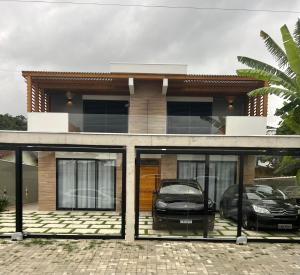 uma casa com portas de vidro e um carro estacionado na frente em Home Aguas da barra Ilhabela em Ilhabela