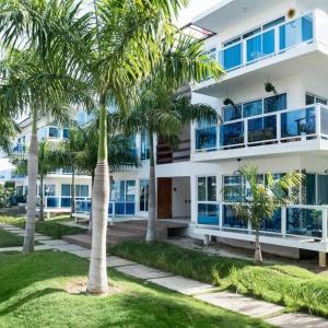 ein Gebäude mit Palmen davor in der Unterkunft Apartamento en Playa Coconut @drvacationsrental in Puerto Palenque
