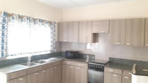 a kitchen with wooden cabinets and a sink and a window at Lashibi Villas in Teshi