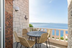 una mesa y sillas en un balcón con vistas al océano en Apartments with pool Vrdoljak, en Omiš