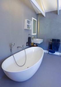 a large white bath tub in a bathroom at Onrus Beach House in Hermanus