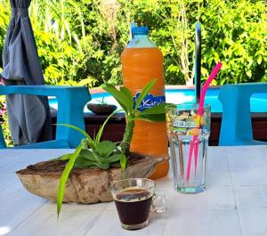 a table with a bottle of orange juice and a drink at Kaz Alberto Guadeloupe in Sainte-Rose