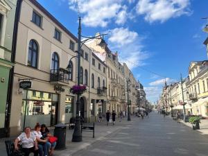 Un groupe de personnes assises sur des bancs dans une rue urbaine dans l'établissement Home & Travel, à Łódź