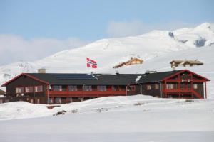 a building with a canadian flag in the snow at Tyinholmen Høyfjellsstuer in Eidsbugarden