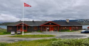 een gebouw met een vlag ervoor bij Tyinholmen Høyfjellsstuer in Eidsbugarden