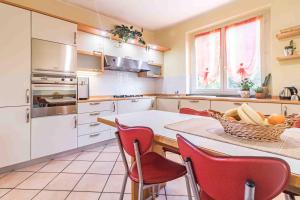 una cocina con armarios blancos y sillas rojas. en Villa Claudia, en Mandello del Lario