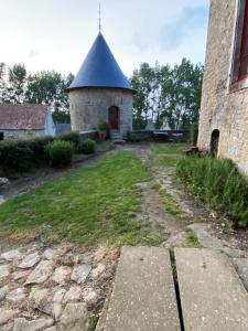 ein Steingebäude mit einem Turm neben einem Gebäude in der Unterkunft La forge de Godincthun in Pernes-lès-Boulogne