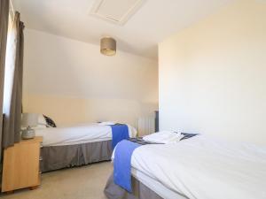 1 dormitorio con 2 camas y mesa con lámpara en Hidden House Hebrides, en Garrabost