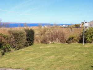 un campo de hierba con el océano en el fondo en Hidden House Hebrides, en Garrabost