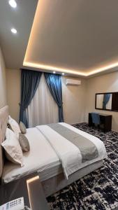 1 dormitorio con 1 cama grande y cortinas azules en رواح للشقق المخدومة- الحوية, en Al Muraysīyah
