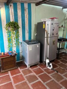 een kat op de vloer naast twee koelkasten bij Beach Airport House in Cartagena