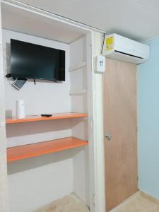 een kamer met een tv en een deur met een plank bij Beach Airport House in Cartagena